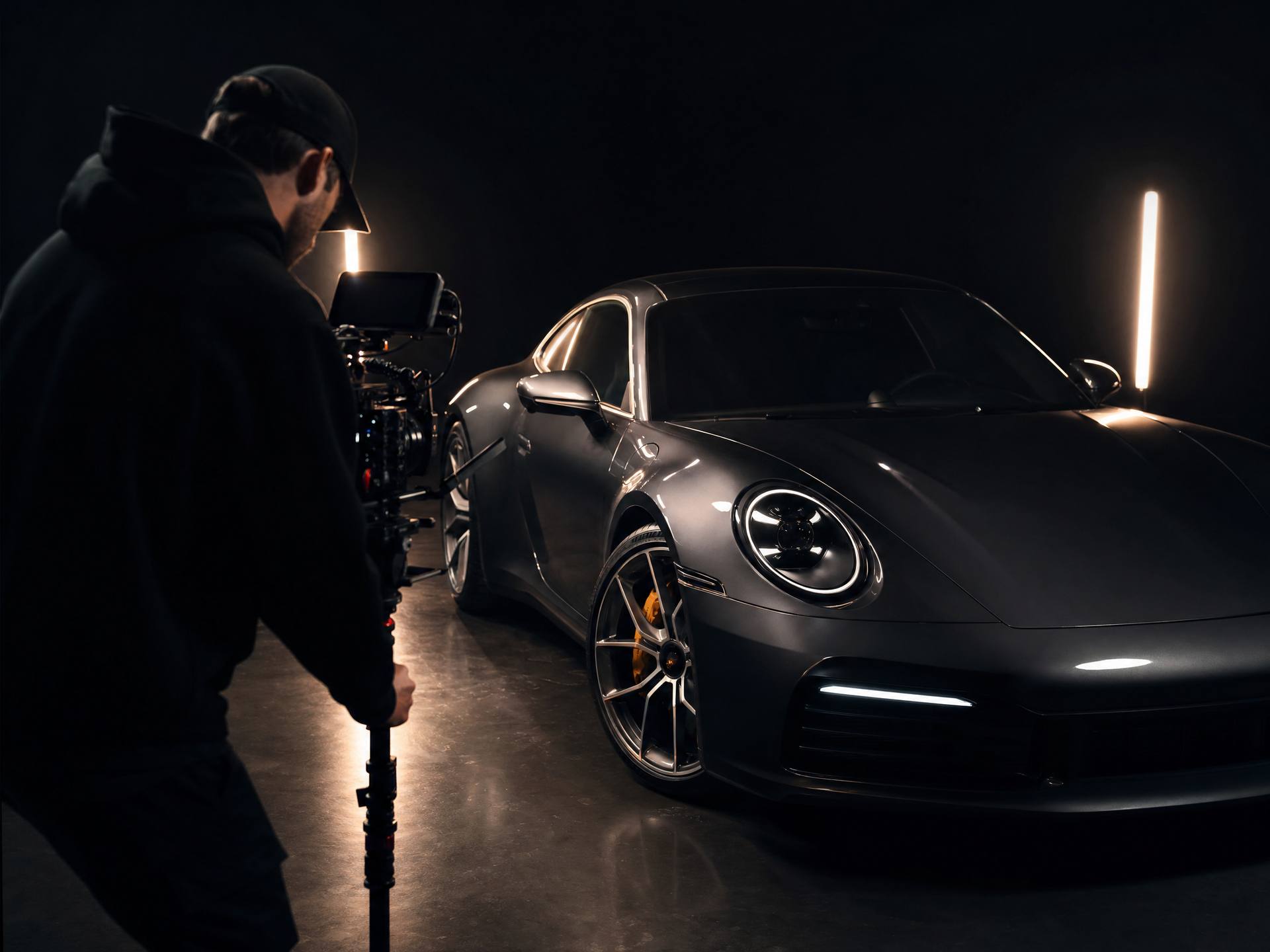 Automotive content creator filming a sports car in a dark studio
